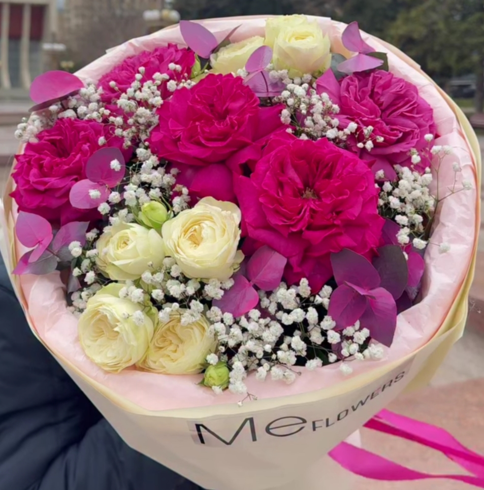 Gabrielle Essense perfume bottle laying flat on a table with green leaves above and below it