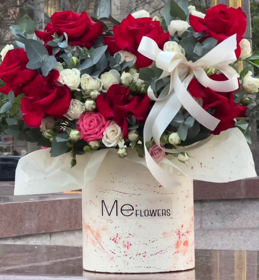 Gabrielle Essense perfume bottle laying flat on a table with green leaves above and below it