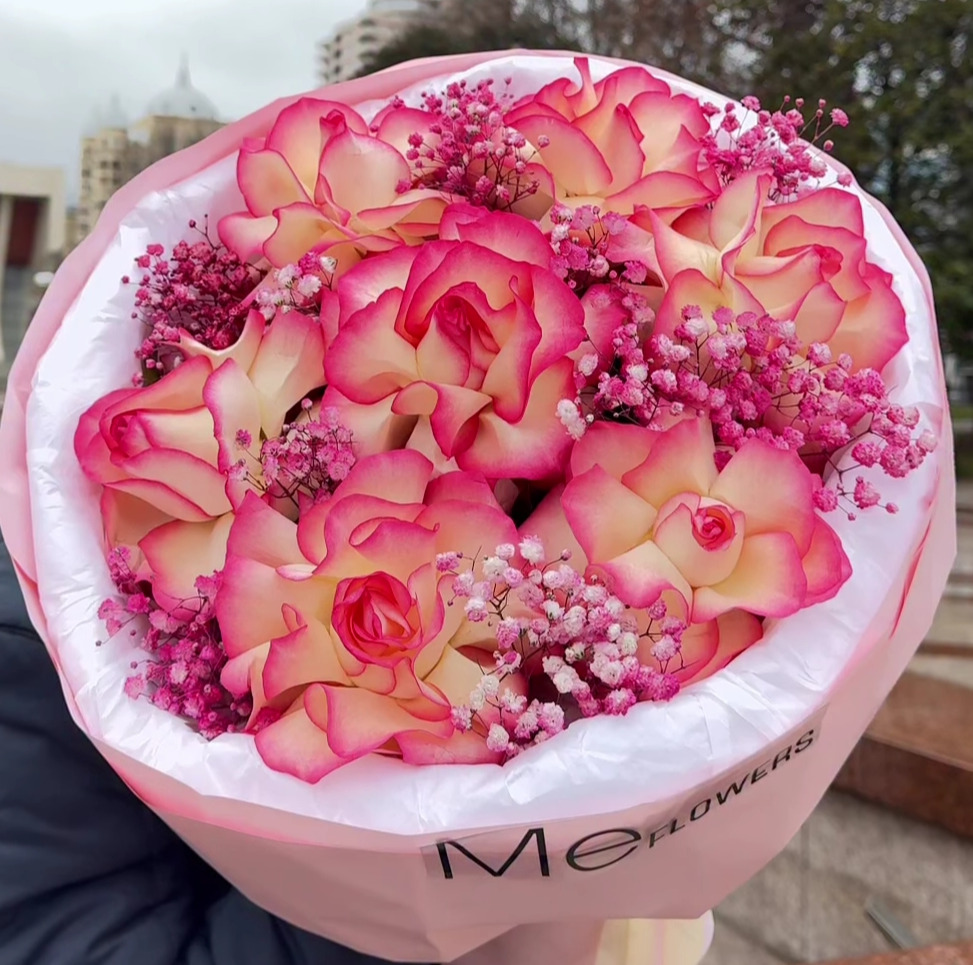 Gabrielle Essense perfume bottle laying flat on a table with green leaves above and below it